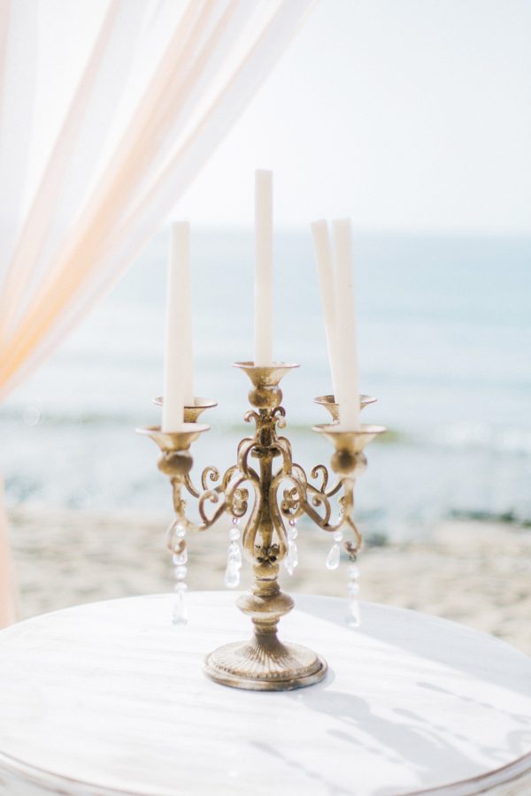 Professional wedding day detail image of a beach wedding ceremony set up decorated with flowers with the backdrop of sand and sea view in Crete.