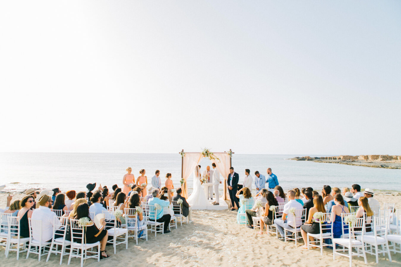 Professional wedding day photoshoot on a beach wedding ceremony, bride and groom getting married under the decorated canopy on one of the beaches in the area of Chania Crete.