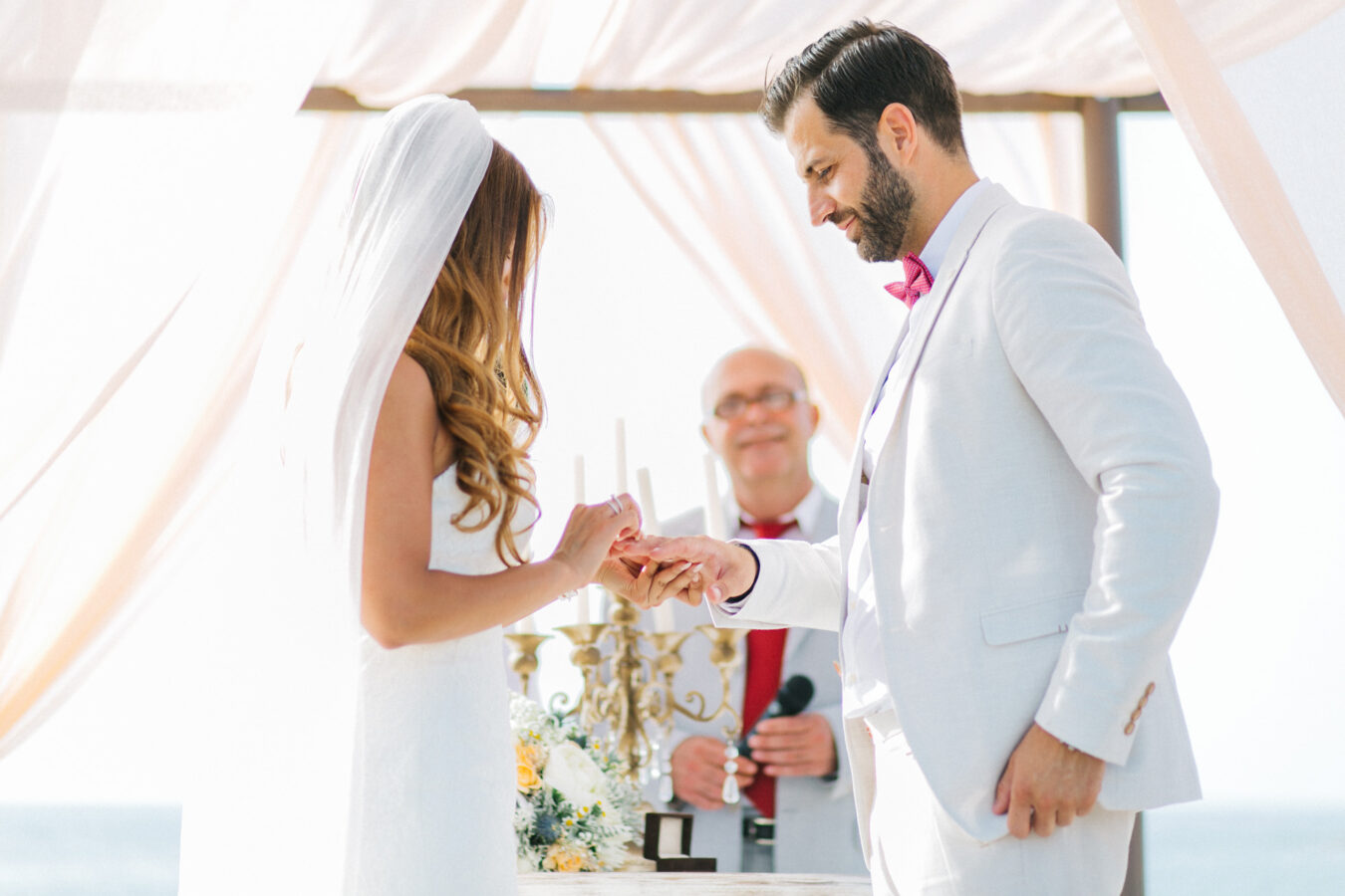 Professional wedding day photoshoot on a beach wedding ceremony, bride and groom getting married under the decorated canopy on one of the beaches in the area of Chania Crete.