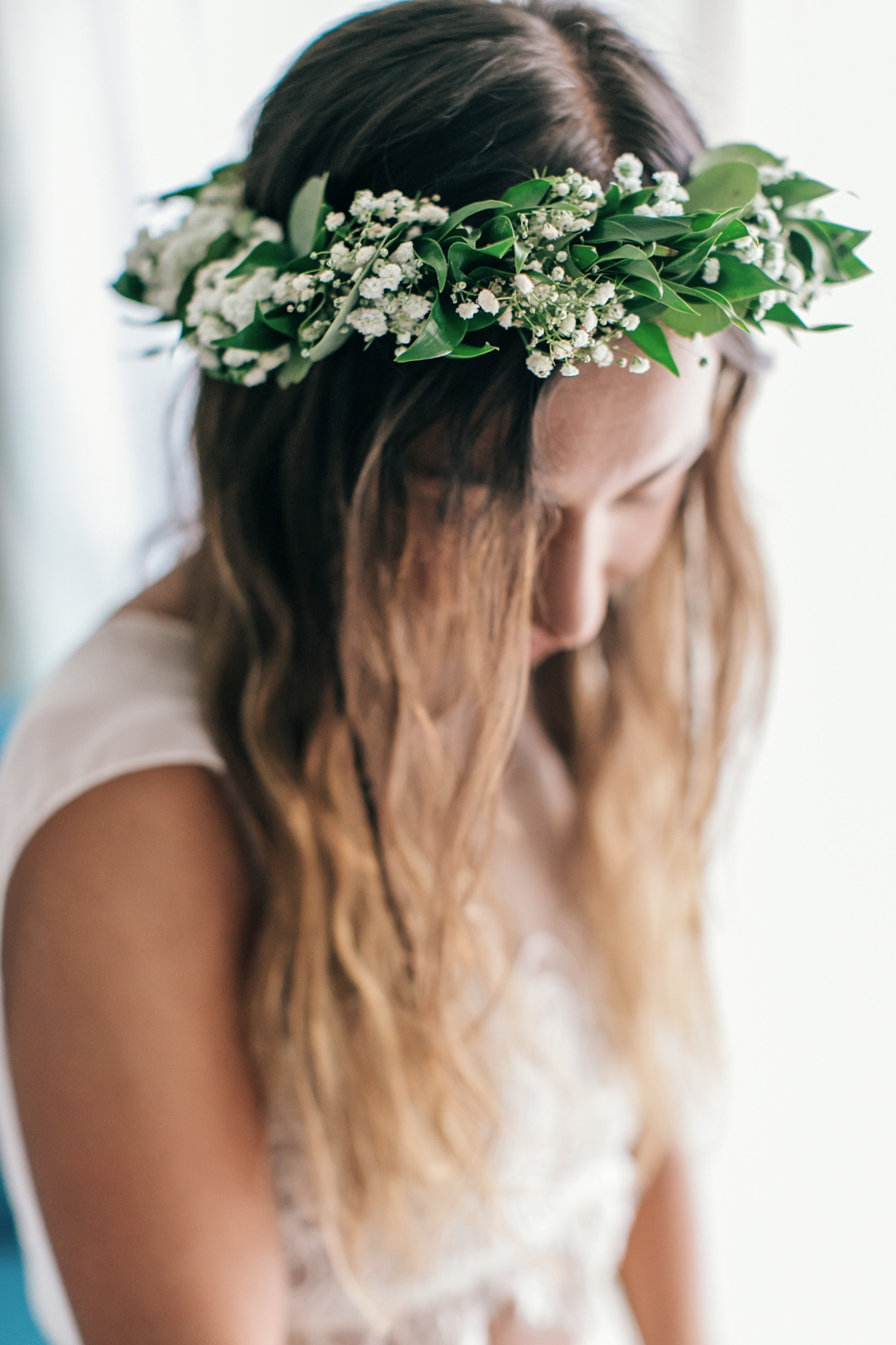Beautiful boho bride wearing a handmade green flower wreath during bridal preparations for a beach ceremony.