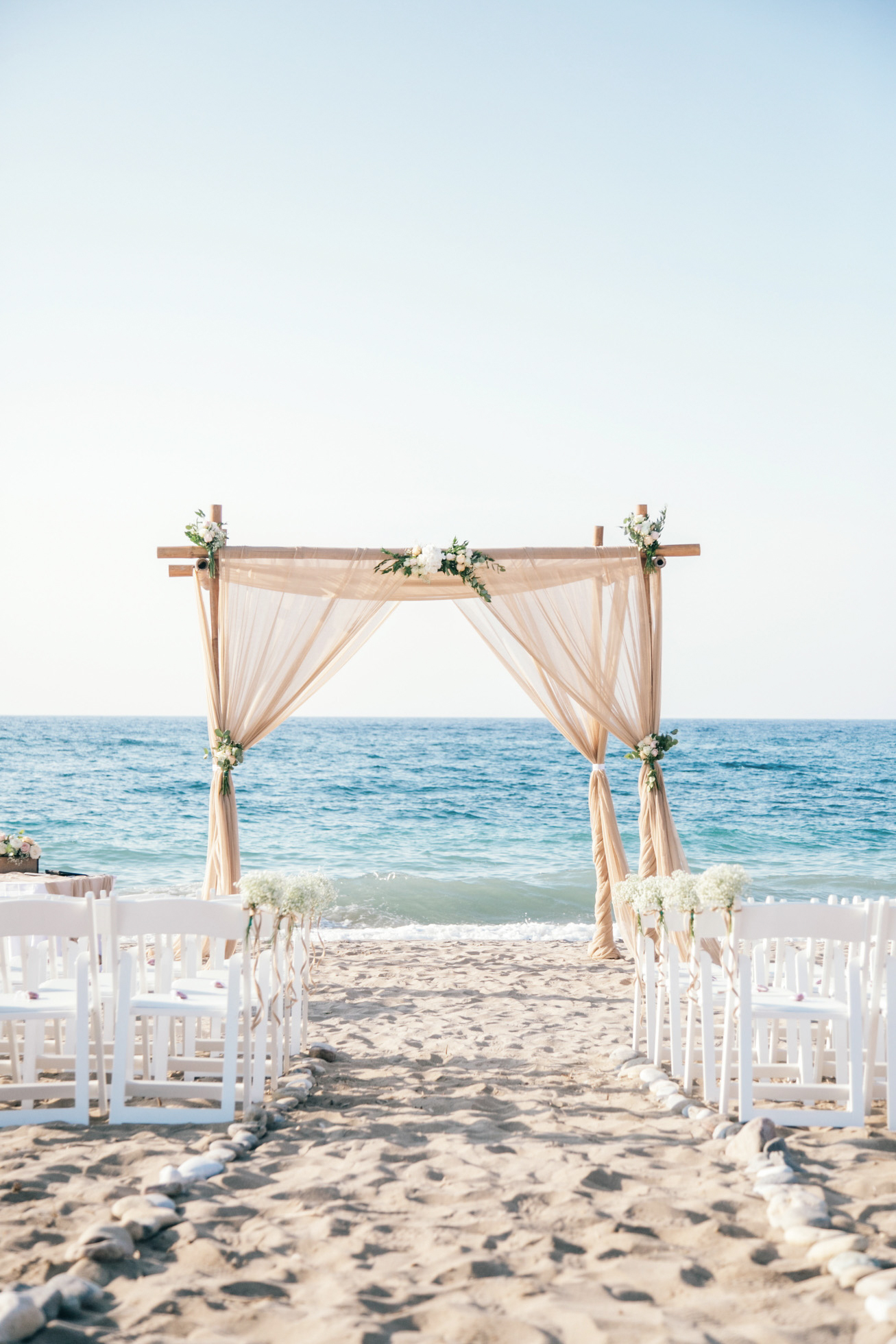Beach ceremony set up in natural tones and fabrics for a symbolic ceremony planned and coordinated by a local wedding planner and photographed professionally.