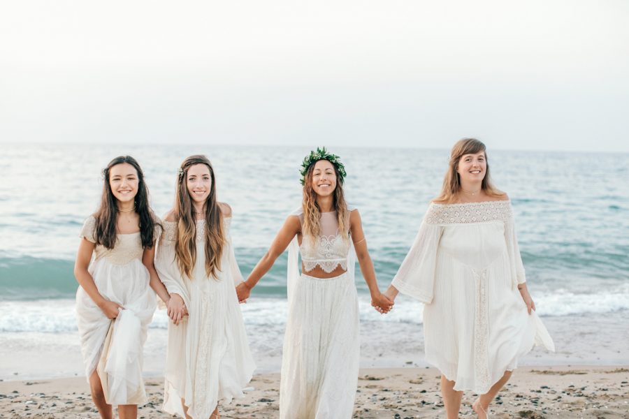 Professional group portrait of the bride and her bridesmaids having fun on the beach after the formalities of the wedding ceremony.