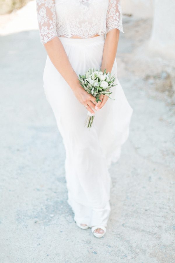 Professional wedding photoshoot in Crete, bride posing with Spinalonga island church and historical ruins in the background.