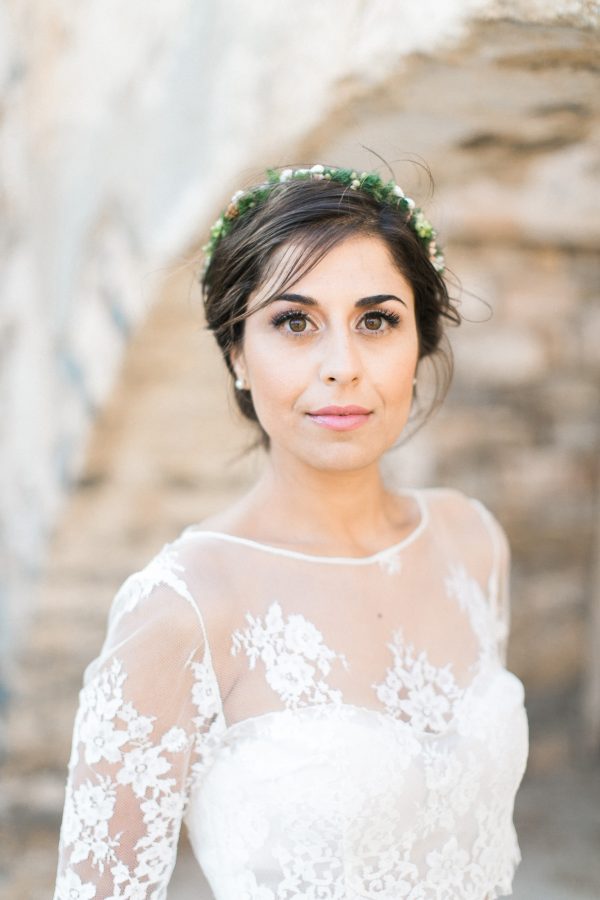 Professional wedding photoshoot in Crete, bride posing with Spinalonga island church and historical ruins in the background.