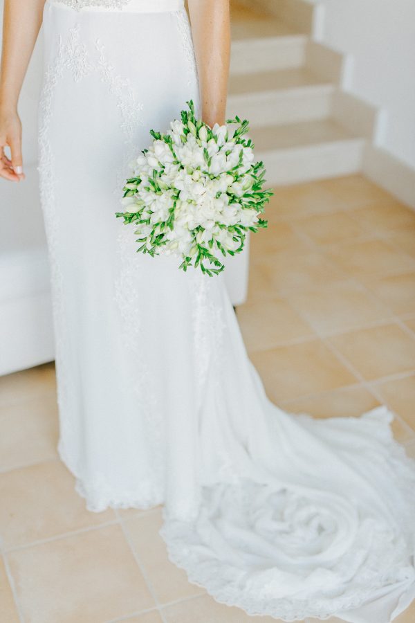 BProfessional image of a bridal bouquet being held by the bride with the background of white Pronovias dress.