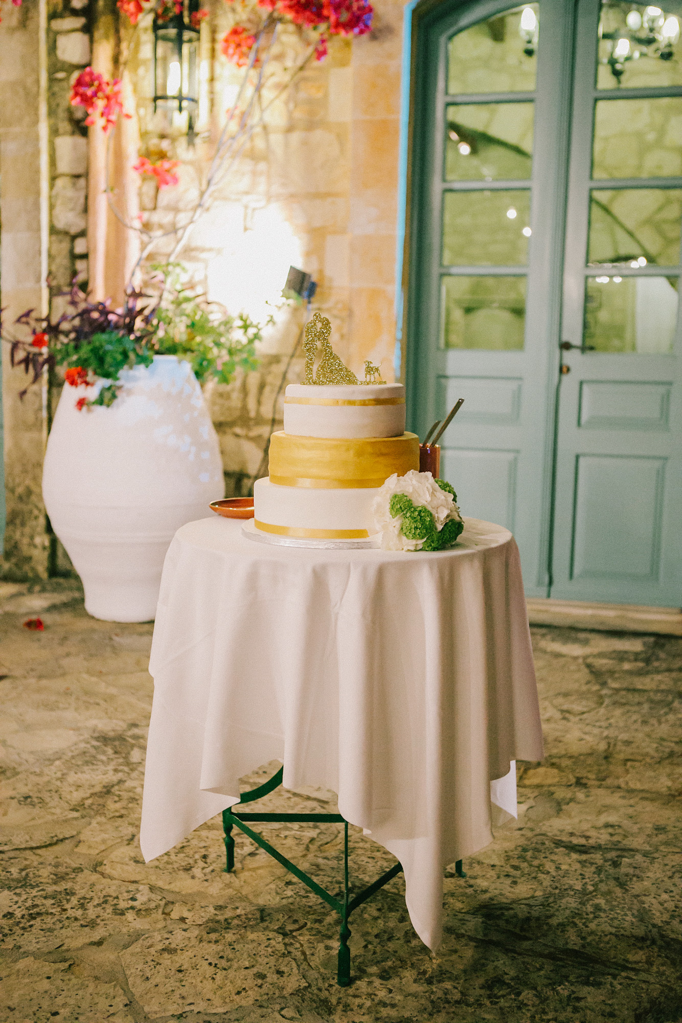 Artisan wedding cake professionally photographed against the background of stony walls and blue Greek windows of Grecotel Agreco farm.