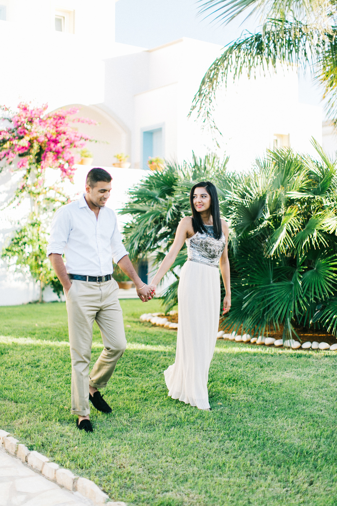 Engaged couple walking along the green lawn of their luxury resort in Crete during their pre wedding engagement photosession.