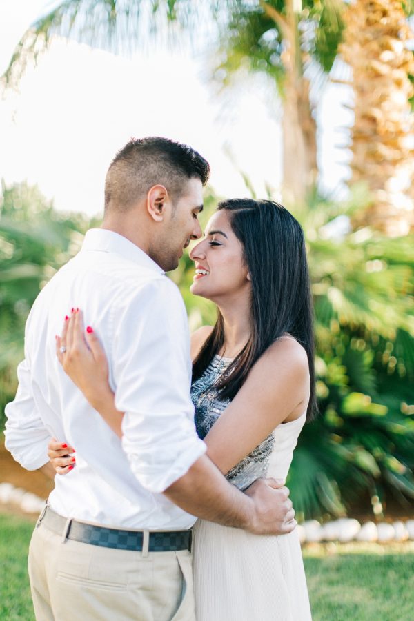 Professional photography portrait of engaged couple posing against the green lawn of their luxury resort in Crete during their pre wedding engagement photosession.