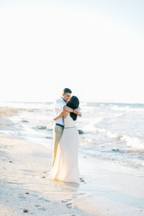 Engaged couple kissing on the beach in Crete during their pre wedding engagement photosession at sunset.