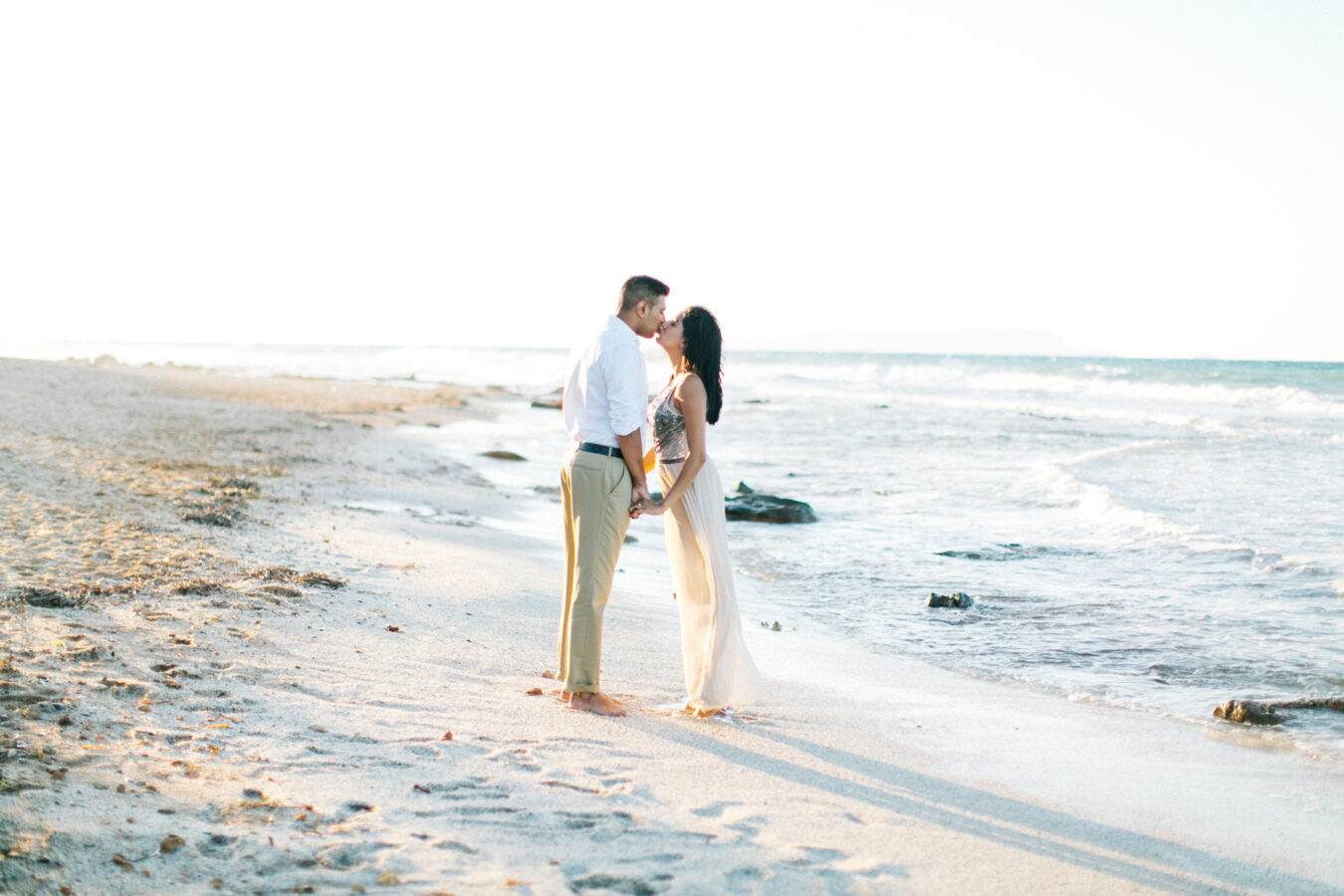 Engaged couple kissing on the beach in Crete during their pre wedding engagement photosession at sunset.