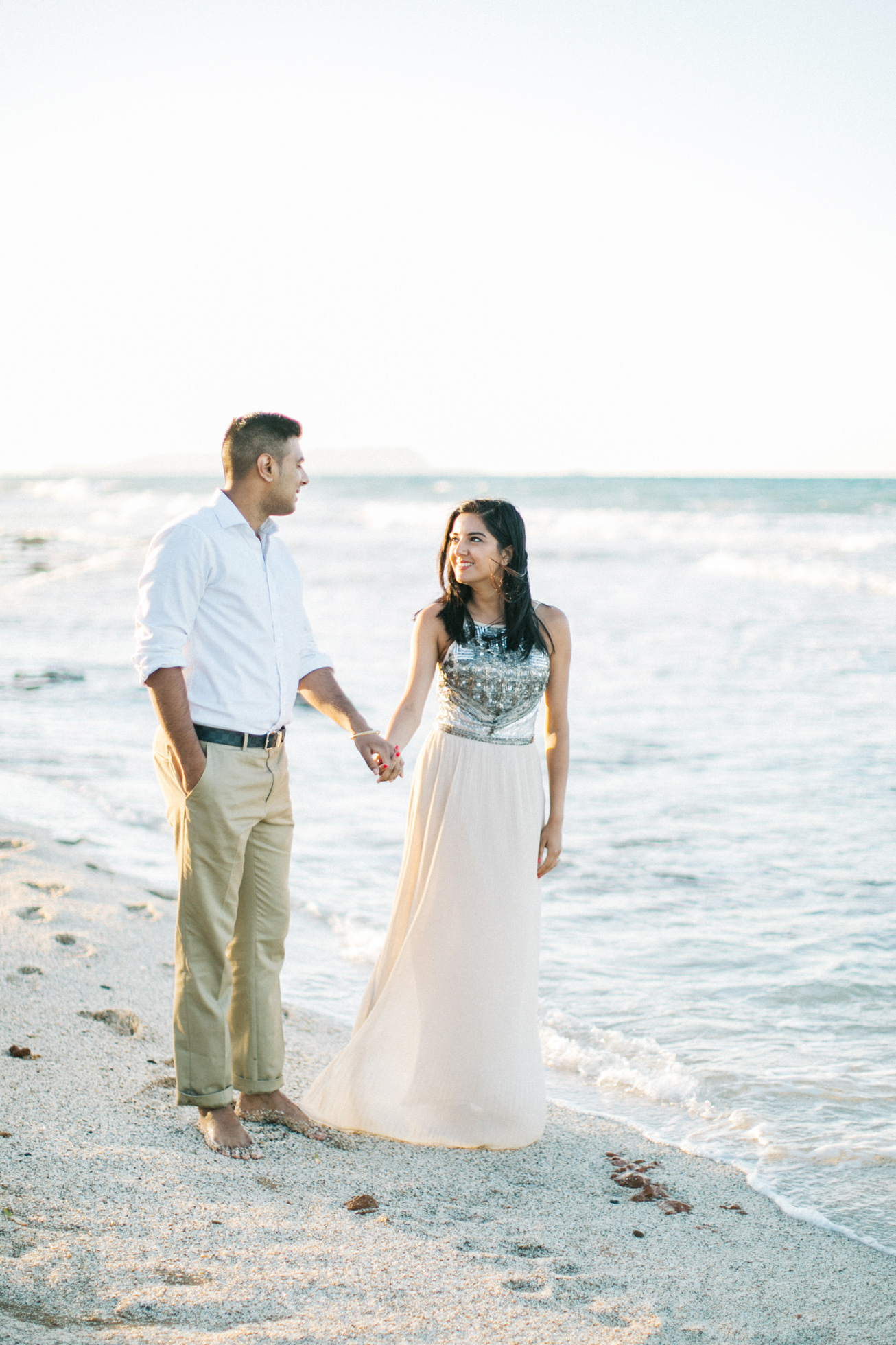 Engaged couple walking along the beach in Crete during their pre wedding engagement photosession at sunset.