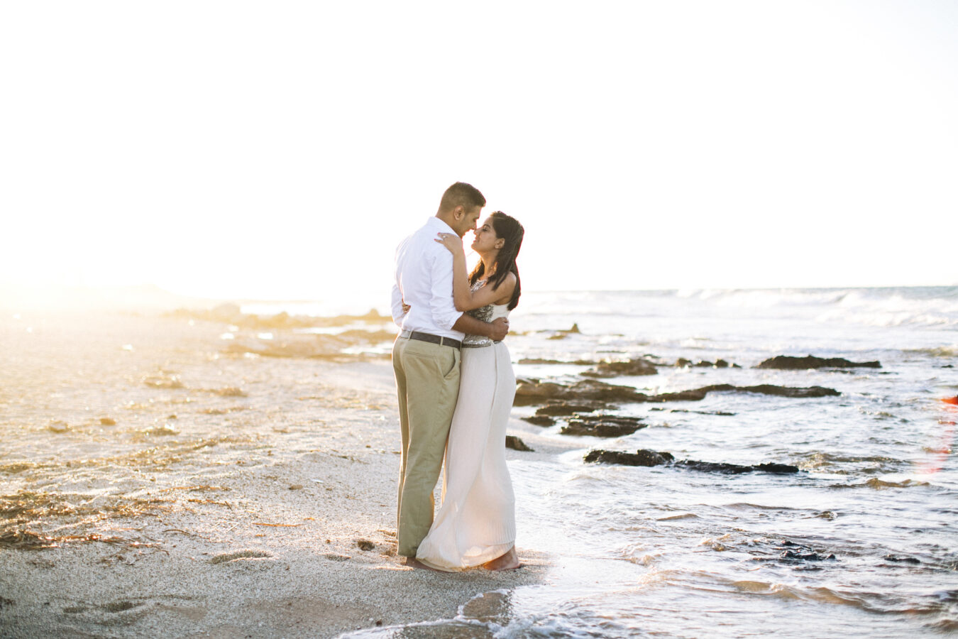 Engaged couple posing on the beach in Crete during their pre wedding engagement photosession with a spectacular sunset backdrop.