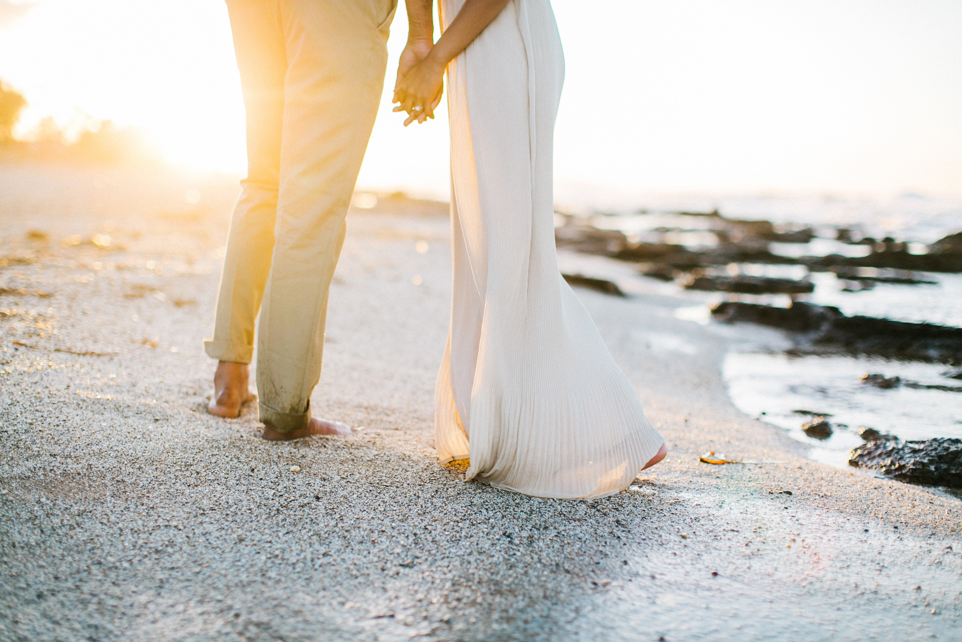 Close up photo of young couple holding hands when posing on the beach in Crete during their pre wedding engagement photosession at sunset.