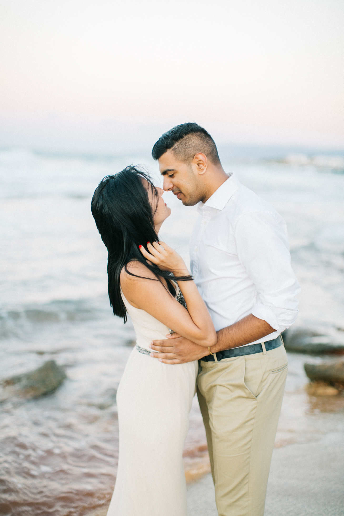 Engaged couple posing for portraits on a stunning sandy beach in Crete during professional pre wedding engagement photoshoot.