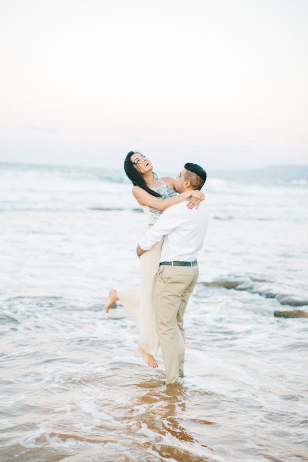 Engaged couple posing for portraits, having fun and laughing on a stunning sandy beach in Crete during professional pre wedding engagement photoshoot.