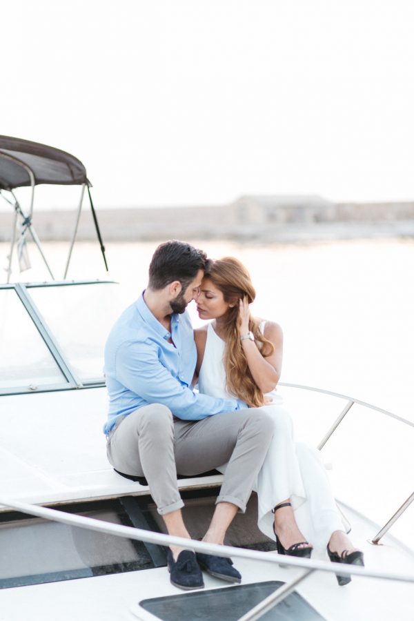 beautiful couple posing for professional photographer in the port of Chania Crete with sunset background of old harbor, surrounded by luxury yachts.