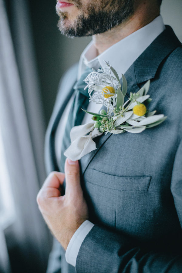 Close up image of an elegant groom's boutonniere. He's posing for portraits on his wedding day in Chania, Crete.