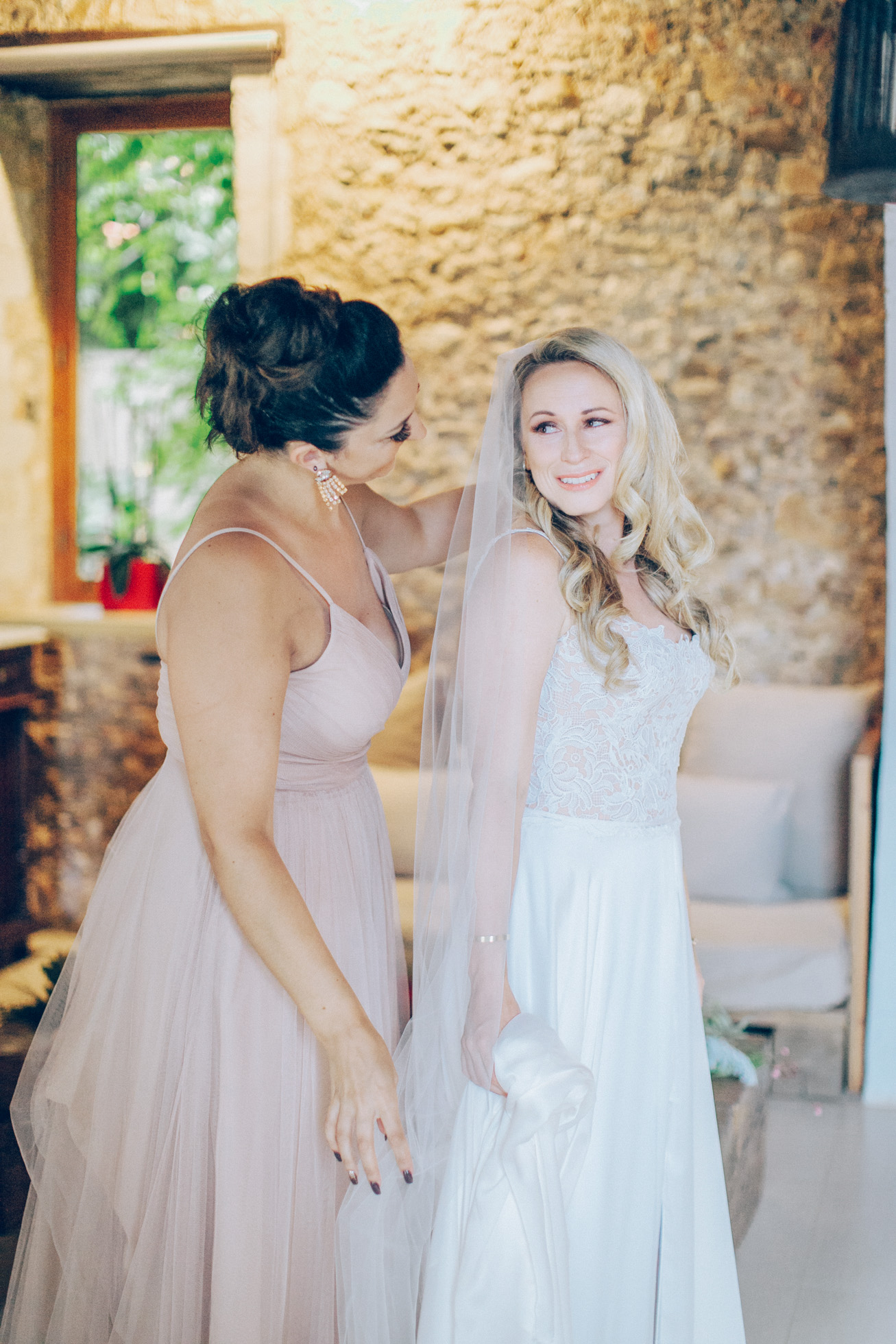 Beautiful bride with her maid of honor posing for the wedding photographer on a summer wedding day in Chania, Crete.