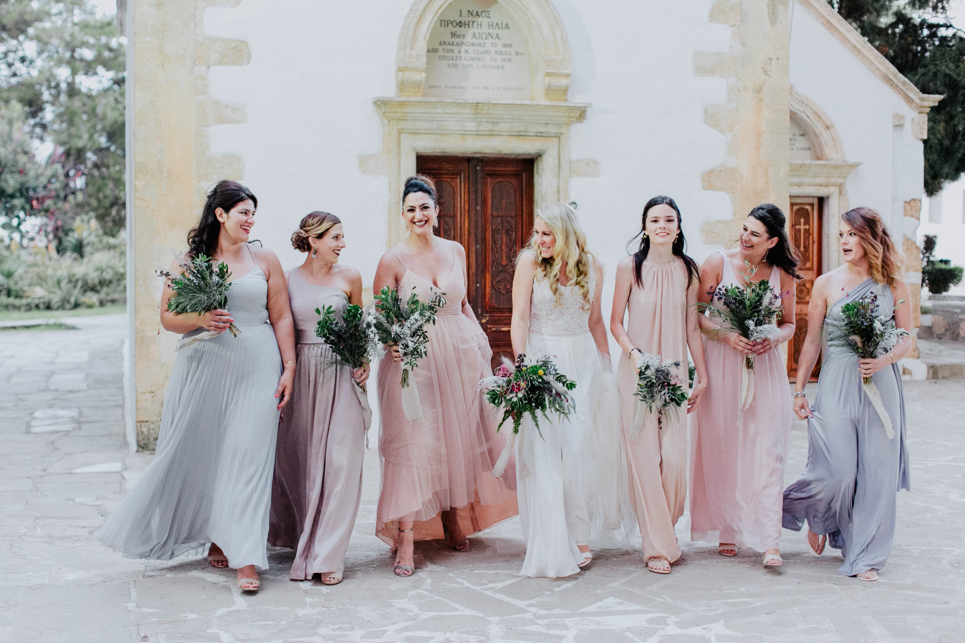 Beautiful bride with group of her bridesmaids posing for the wedding photographer on a summer wedding in Chania, Crete.