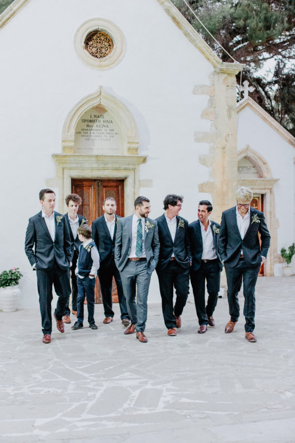 Stylish groom with group of his groomsmen posing for the wedding photographer on a summer wedding in Chania, Crete.