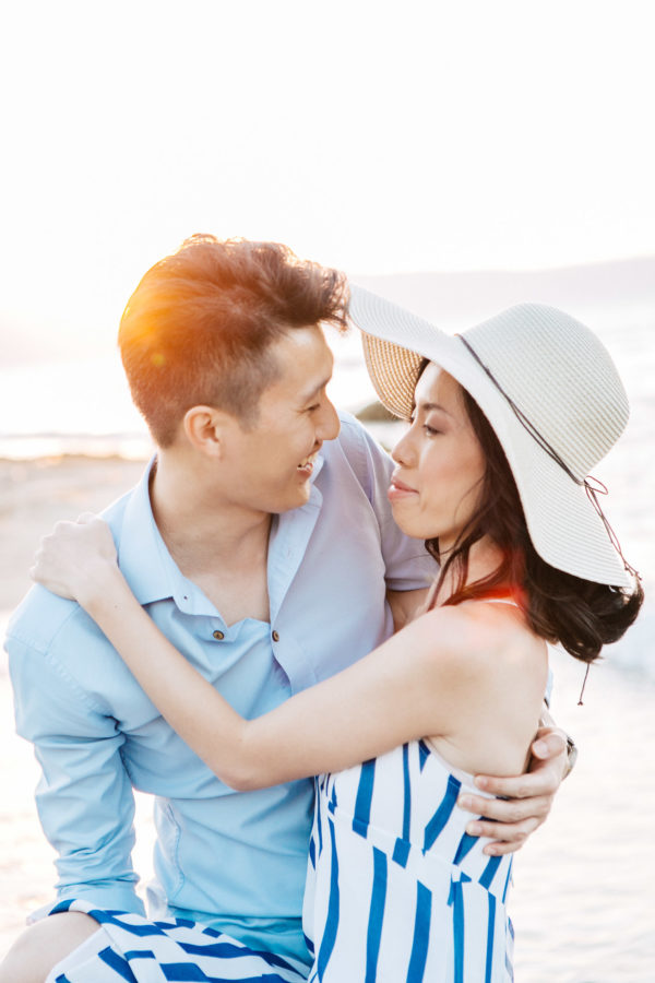 Happy international couple wearing summer clothing is posing for professional photographer team during their beach wedding photoshoot on the secluded shores of Rethymno town, Crete, Greece.