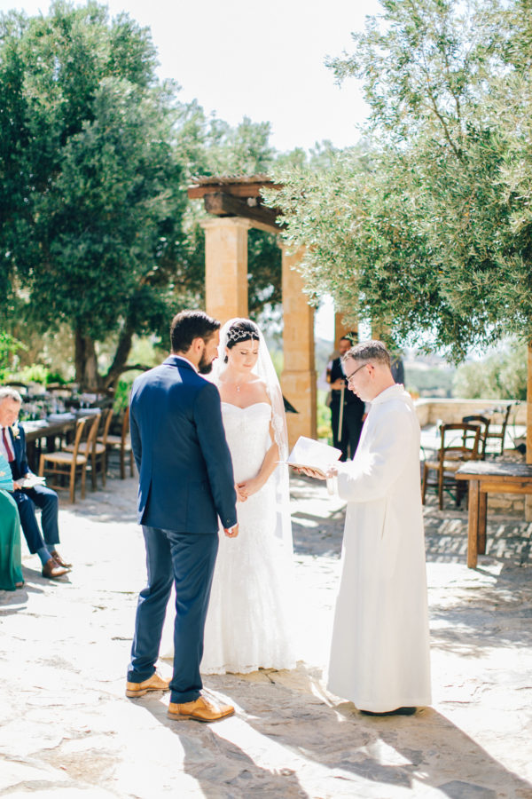 Candid image of an elegant bride and groom getting married in Agreco Farm in Crete, Greece, captured by their wedding photographer.