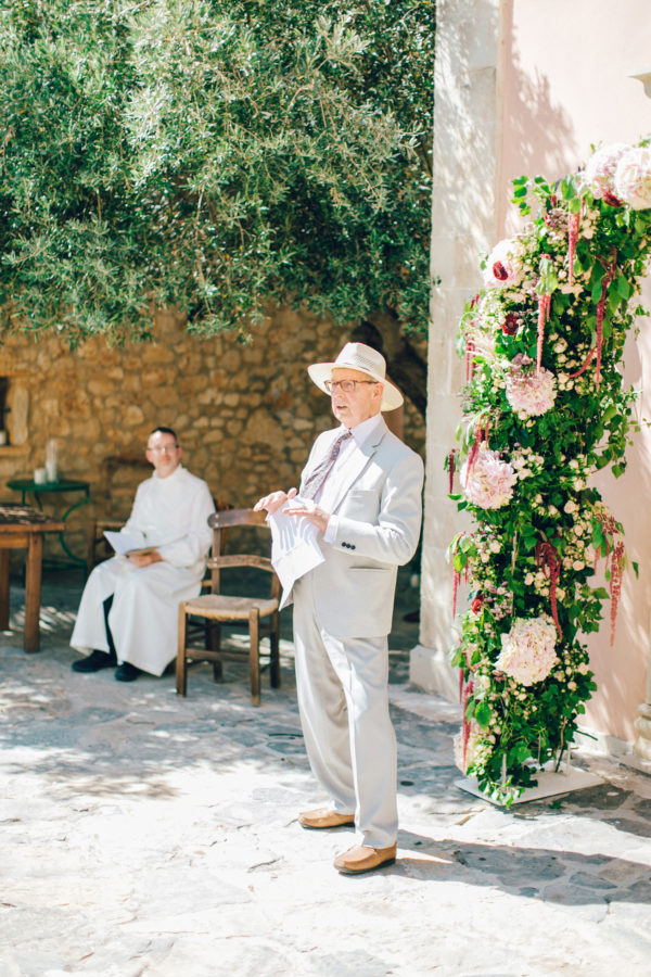Candid image of an elegant wedding minister giving a speech on a destination wedding day in Agreco Farm in Crete, Greece, captured by their wedding photographer.