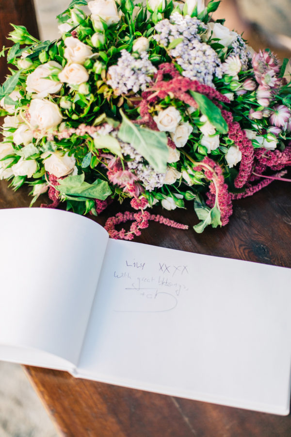 Rich floral decorations and wish book details created by Fabio Zardi and captured by wedding photographer during a destination wedding in Agreco farm in Crete.