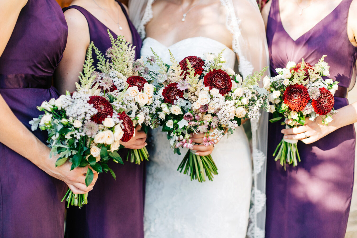 Stunning bride and her classy elegant bridesmaids wearing matching purple dresses and holding flower bouquets posing for formal portraits after the wedding ceremony at Agreco Farm in Crete, Greece.