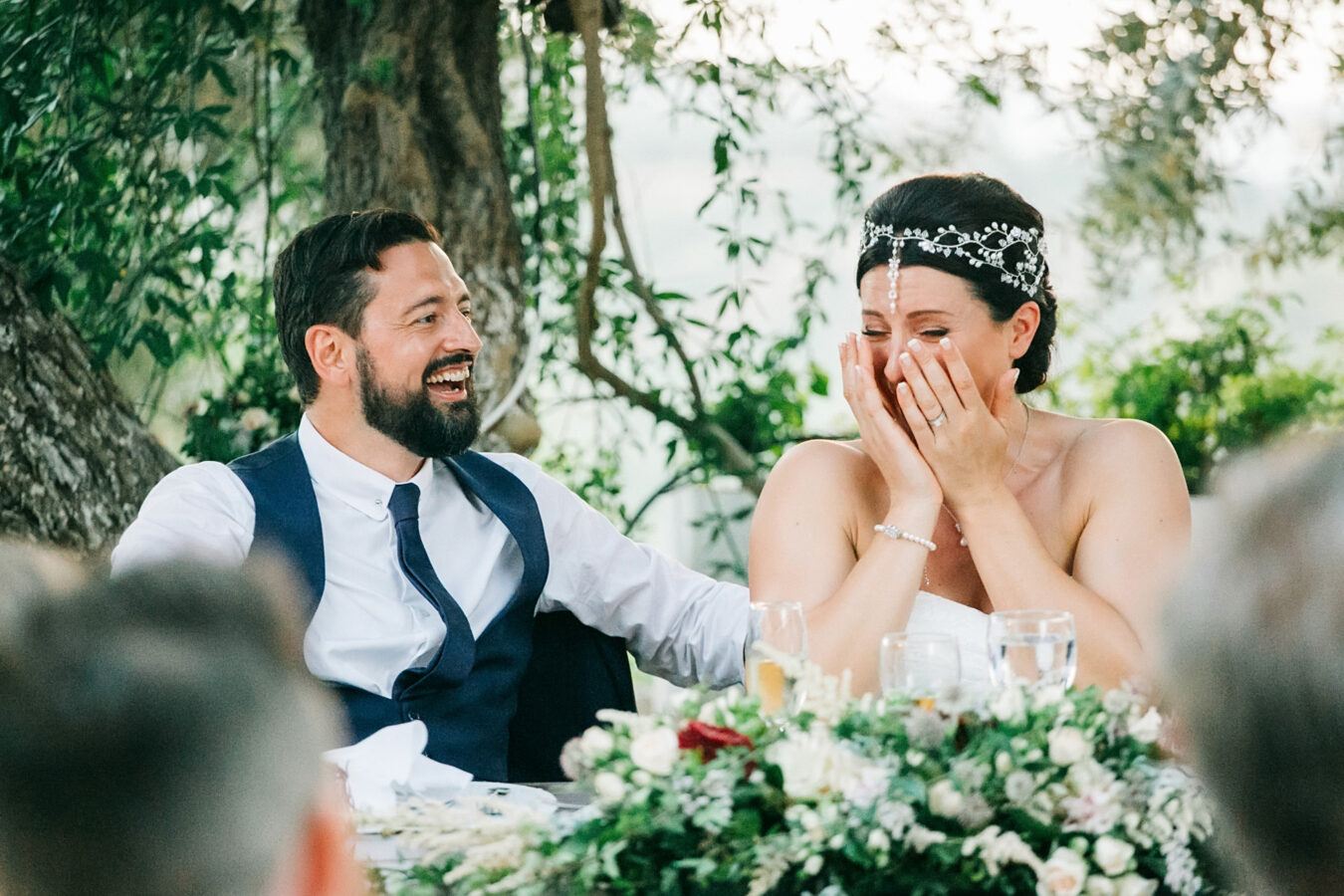 Candid image of bride and groom having time of their life during wedding speeches at dinner in Agreco Farm in Crete.