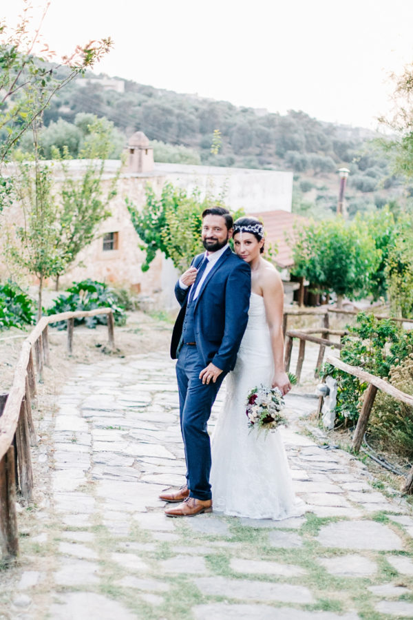 Stunning and happy bride and groom posing for portraits for their photographer on a destination wedding day in Agreco Farm, Crete.