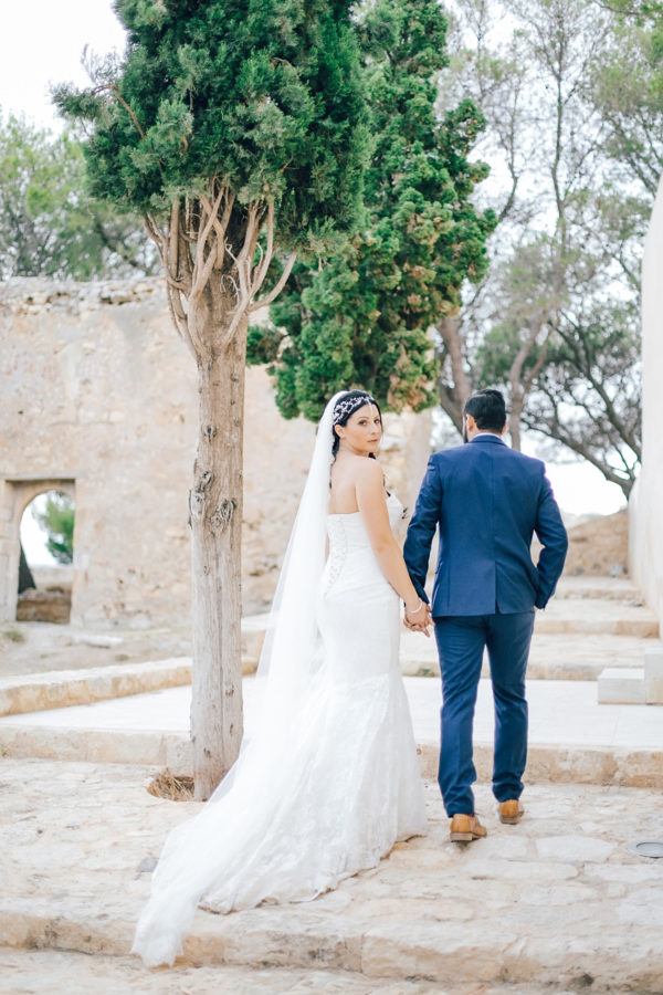 Fine art wedding portraits of the newly wedded couple posing for professional destination wedding photographer at Fortezza of Rethymno in Crete, Greece.