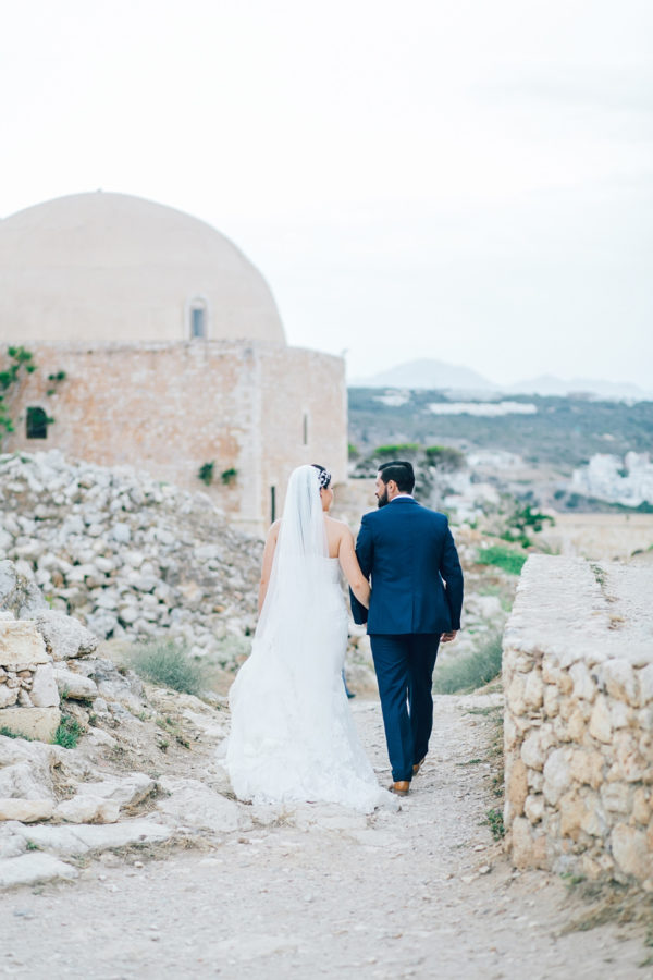 Fine art wedding portraits of the newly wedded couple posing for professional destination wedding photographer at Fortezza of Rethymno in Crete, Greece.