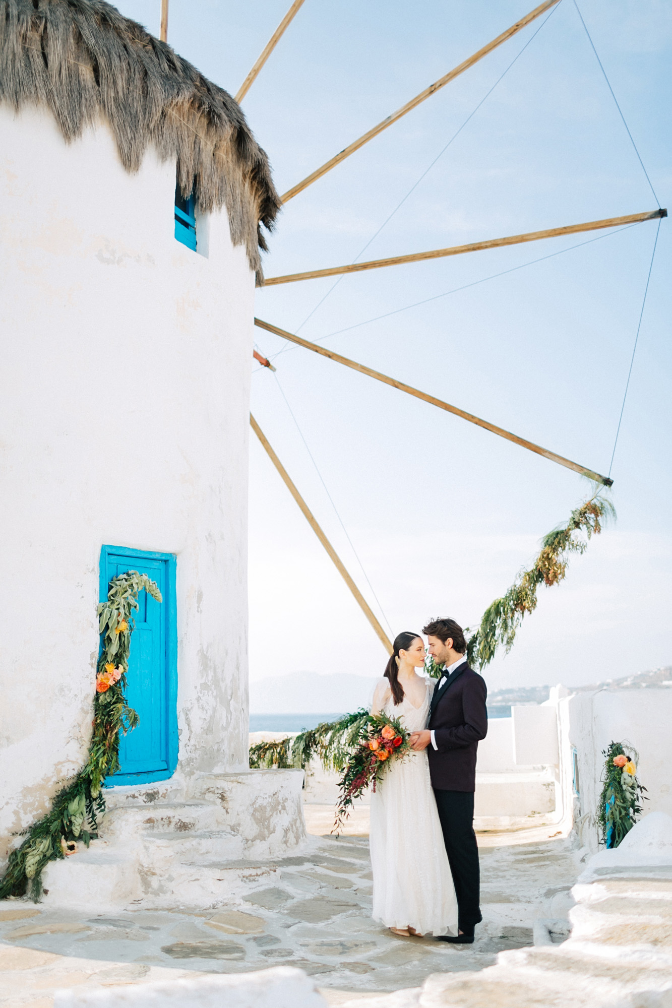 Stylish bride and groom on their destination wedding in Mykonos, posing under the windmills.