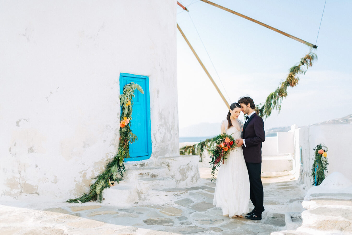 Stylish bride and groom on their destination wedding in Mykonos, posing under the windmills.