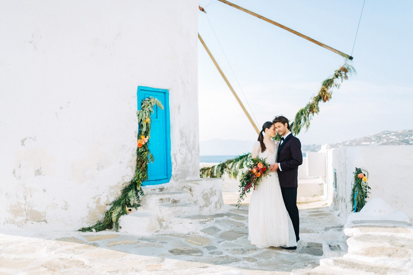 Stylish bride and groom on their destination wedding in Mykonos, posing under the windmills.