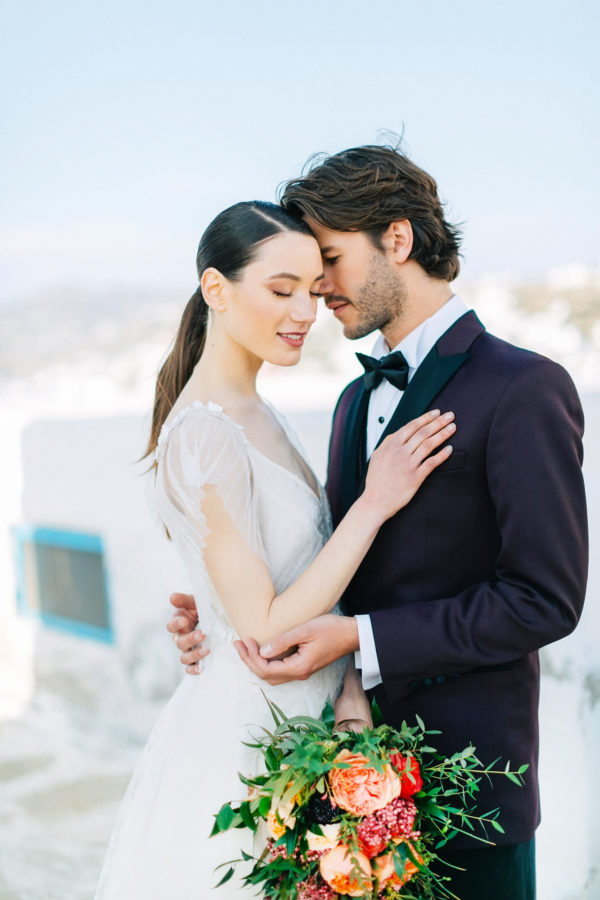 Stylish bride and groom on their destination wedding in Mykonos, posing under the windmills.