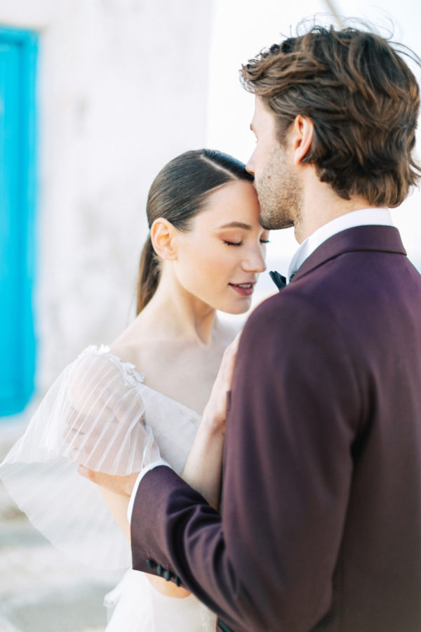 Stylish bride and groom on their destination wedding in Mykonos, posing under the windmills.