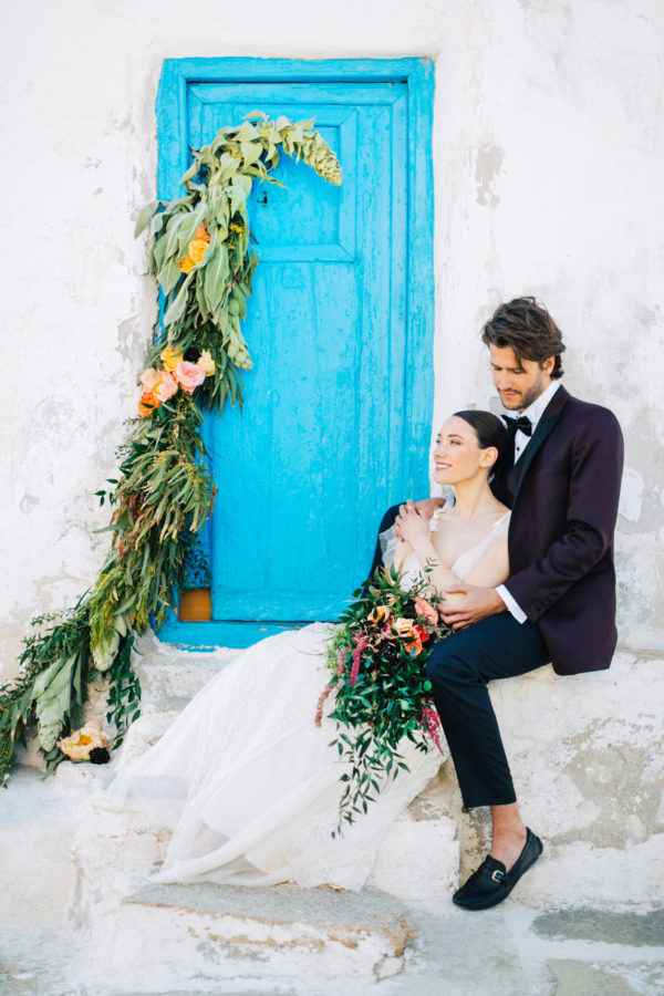 Stylish bride and groom on their destination wedding in Mykonos, posing under the windmills.