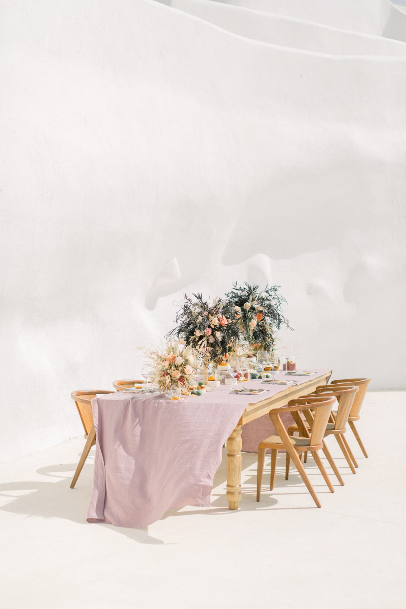 Unique wedding dinner and reception table setup in Santorini accented with stained glass tile menus and pampas grass arrangements.