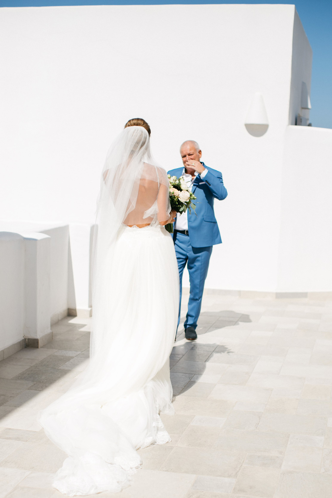 Bride's first look with her father at luxury white wedding in Santorini island, Greece.
