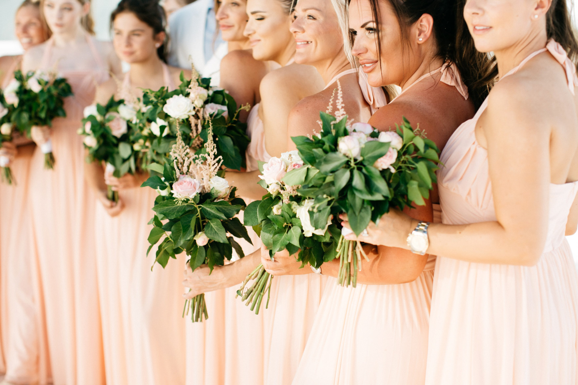 Bridal party holding flower bouquets at Le Ciel wedding estate in Santorini island, Greece.