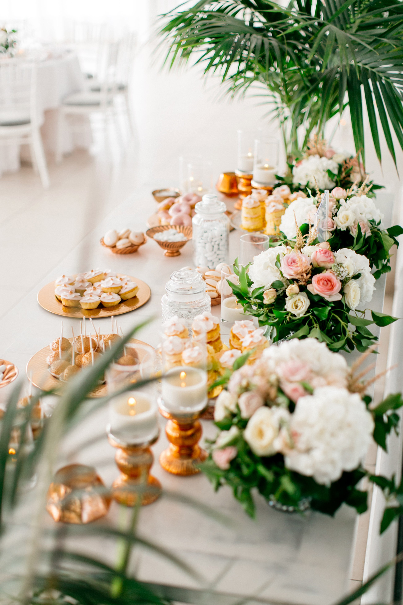 Wedding dinner details and reception decoration in white and blush pink including the sweets table at Le Ciel wedding estate in Santorini island, Greece.