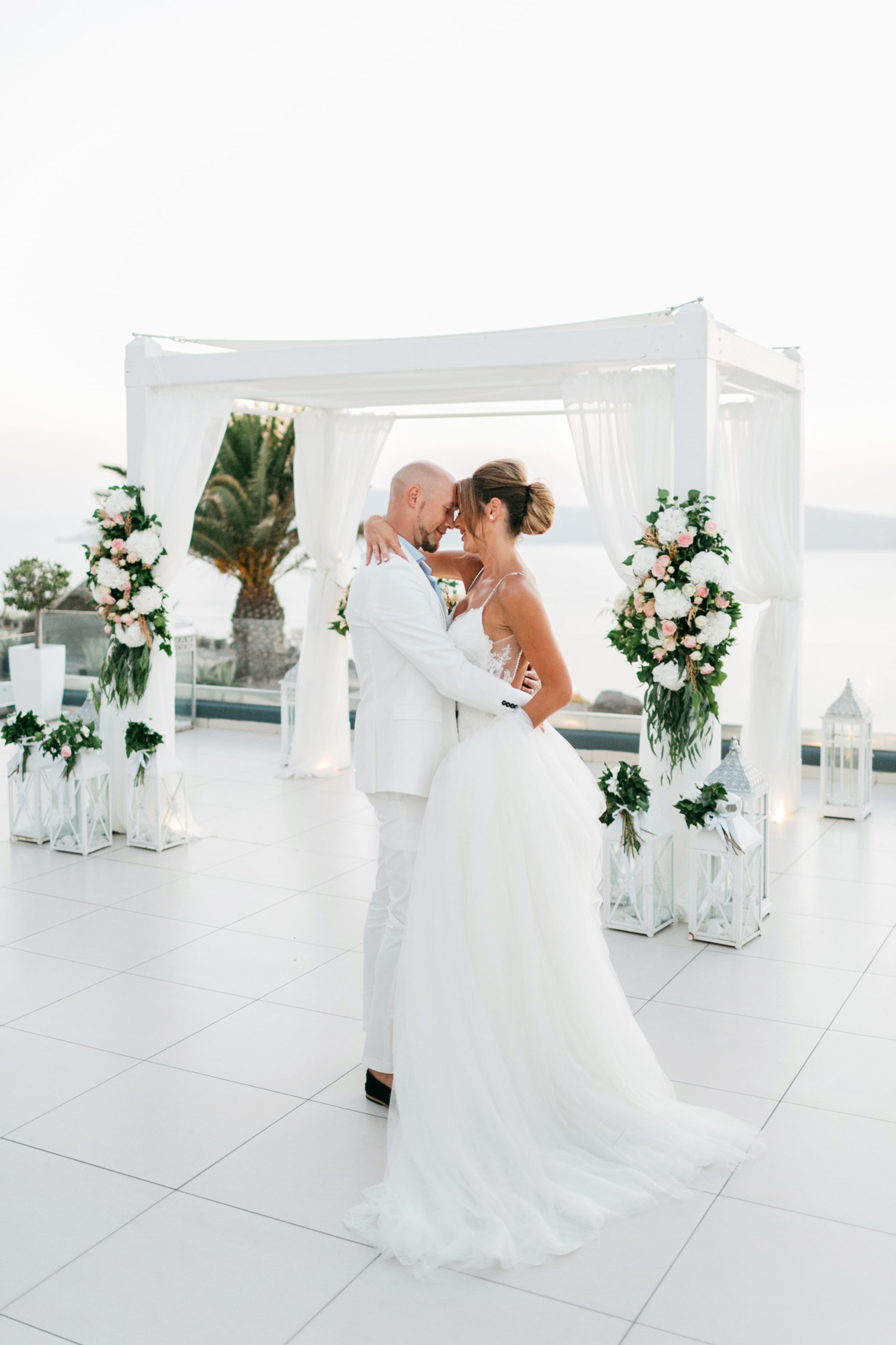 Bride and groom posing for their sunset wedding day portraits at Le Ciel wedding estate in Santorini island, Greece.