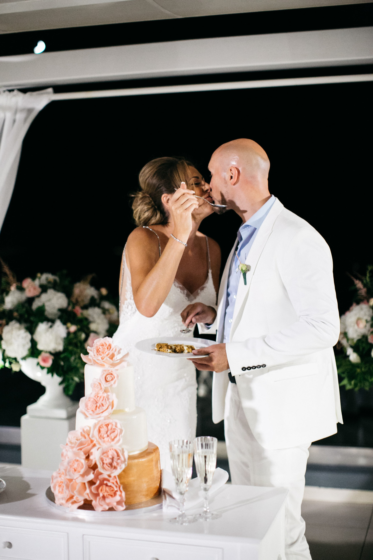 Cake cut and bride and groom sweet kiss at Le Ciel wedding estate in Santorini island, Greece.
